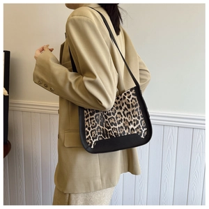 Detail of trendy leopard print shoulder bag with black trim worn with a beige blazer