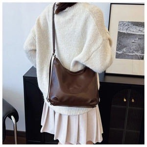 Deep brown matte leather large capacity hobo bag worn over the shoulder by a model