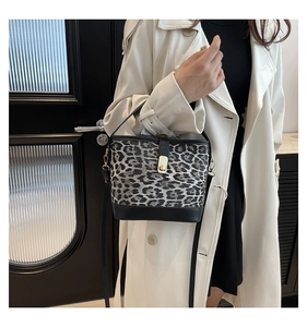 Fashionable leopard print bucket bag with gold clasp shown on a model with white coat