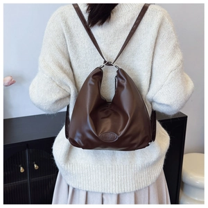 Detailed back view of a minimalist deep brown leather tote bag worn over a knit sweater