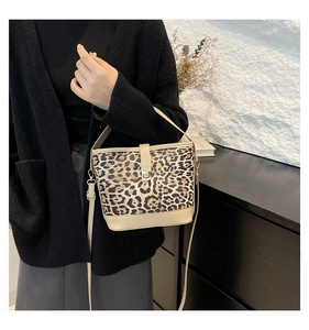 Leopard print bucket bag with beige leather trim and gold buckle shown on a model
