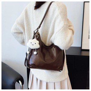 Detail of dark brown PU leather Hobo bag with white cloud plush pendant on a model