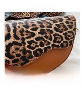 Detail view showing leopard print saddle bag texture with premium brown leather finishes