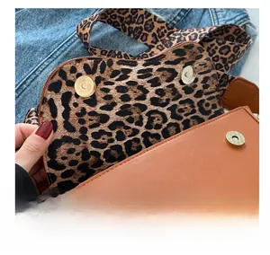 Detail of magnetic hardware closure on a brown leather saddle bag with leopard print