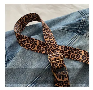 Detail of leopard print wide strap with gold metal buckle on denim background