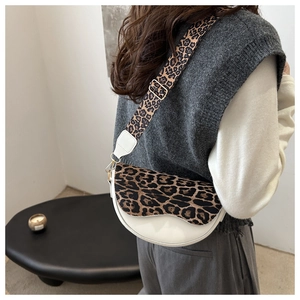Chic saddle bag featuring leopard print strap and cream white leather worn by model