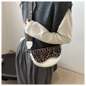 Detail of white saddle bag with leopard print flap and wide shoulder strap on model