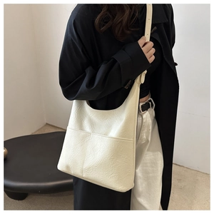 Détail du sac cabas blanc cassé avec texture en cuir plissé et poche avant pratique