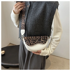 Detail of white leather saddle bag with leopard print flap and wide shoulder strap