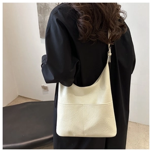 Detail of off-white minimalist hobo bag showing stitching on soft leather shoulder strap