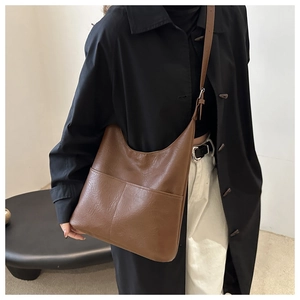 Detail of dark brown leather tote bag featuring dual front pockets and adjustable strap