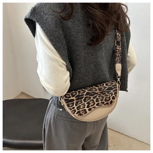 Detail of saddle bag with leopard print flap and wide strap worn by a female model