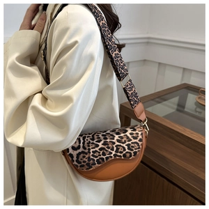 Leopard print saddle bag detail with wide shoulder strap shown on a female model