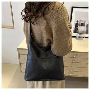 Detail of black leather shoulder bag showing the fine texture and decorative stitching