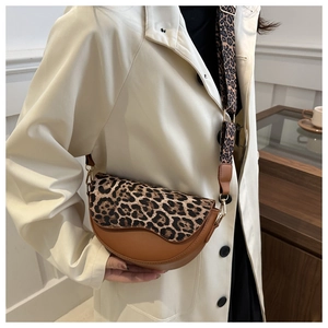Detail of leopard print saddle bag with wide shoulder strap worn by a model