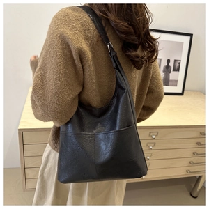 Vue latérale d'un grand sac hobo noir vintage en similicuir porté par un mannequin