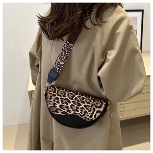 Leopard print saddle bag with wide strap styled on a camel coat in a cozy room