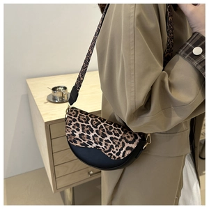 Detail of leopard print saddle bag with wide strap worn over a classic beige coat