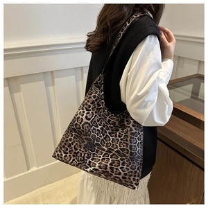 Side view of a vintage leopard print tote bag with a wide shoulder strap worn by a model