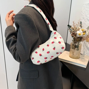 Sac croissant en velours côtelé blanc avec imprimé fraises rouges porté à l'épaule