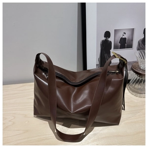 Detailed view of deep brown leather tote bag on a wooden table with lifestyle decor