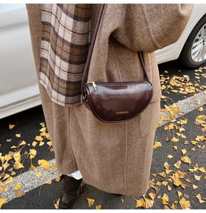 Detail of a dark brown croissant bag with golden zipper on a vintage autumn outfit