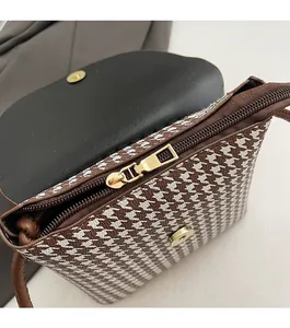 Detailed close-up of smooth gold metal zipper and inner lining on houndstooth bucket bag