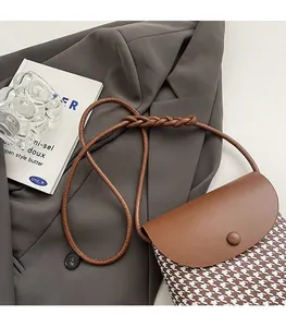 Detail of vintage brown leather and houndstooth crossbody bag with woven shoulder strap