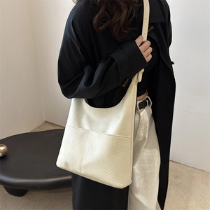 Grand sac hobo crème à texture plissée avec bandoulière réglable porté par un mannequin
