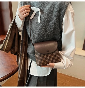 Close-up of vintage houndstooth shoulder bag with brown leather strap and round buckle