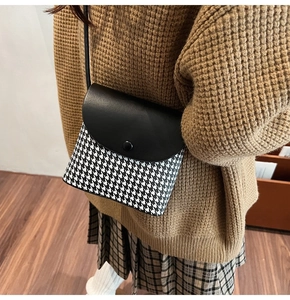 Side view of houndstooth crossbody bucket bag on a model wearing brown sweater