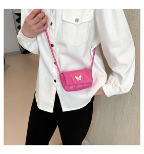 Detail of pink mini crossbody bag featuring a white butterfly metal buckle and rope strap