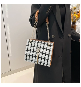 Dettaglio borsa in tweed a scacchi con fibbia a S dorata e frange eleganti