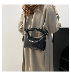 Detail of woven black crossbody bag featuring a scrunched handle and metal buckle