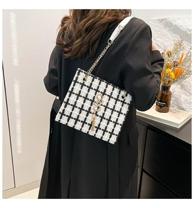 Detailed back view of model wearing black and white tweed crossbody bag with gold chain
