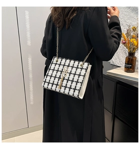 Dettaglio borsa in tweed a scacchi bianco e nero con catena d'oro e nappina