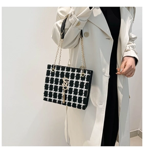 Detail of black and white checkered tweed shoulder bag with chain strap and S-logo