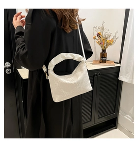 Detail of white woven hobo bag with unique ruched cloud handle and gold metal chain strap