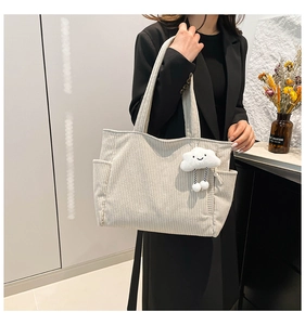 Detailed view of beige corduroy tote bag with vertical stripes and cloud plush charm