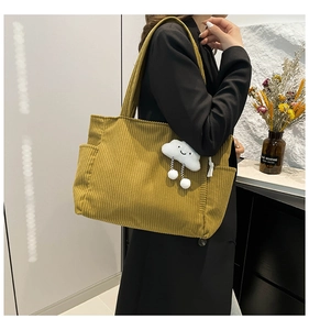 Detail of mustard yellow corduroy tote bag featuring a cute white cloud plush pendant