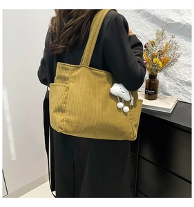 Detail of mustard corduroy tote bag with cute cloud charm showing its large side pocket