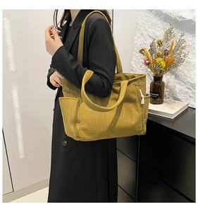 Detail of mustard yellow corduroy tote bag showing ribbed texture and side pocket on shoulder bag