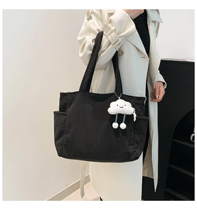 Detail of black corduroy tote bag featuring side pockets and a cute cloud plush pendant