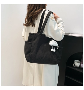 Detail of black corduroy tote bag showing ribbed texture and cloud doll charm
