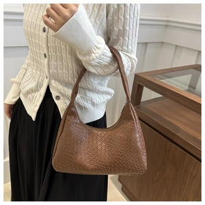 Close-up of brown woven texture and crescent shape on minimalist leather shoulder bag