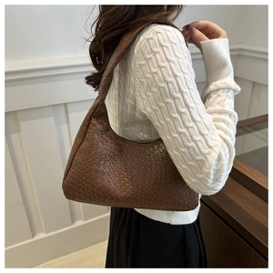 Close-up of brown woven texture hobo bag worn with a casual white sweater