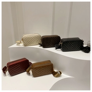 Detailed display of quilted square camera bags in five colors on minimalist tiered steps