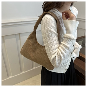 Détail d'un sac à bandoulière en cuir tressé marron clair avec motif à carreaux fins