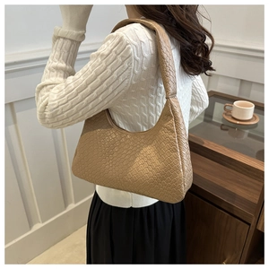 Khaki woven hobo bag with thick texture worn on shoulder in a cozy minimalist setting