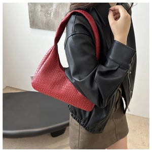 Side view of red woven hobo bag carried by a model in a minimalist modern interior
